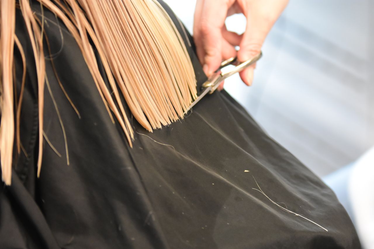 A stylist cutting a client's hair in a bright salon